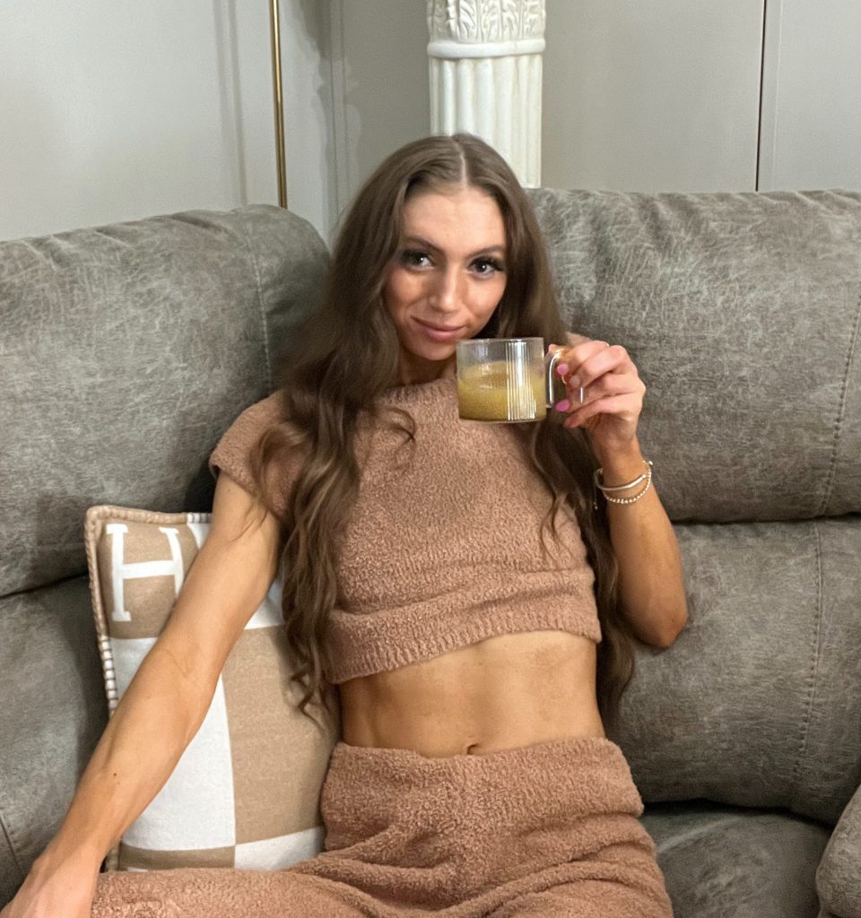 Drinking Latte on couch in fuzzy brown matching set, gold mirror, hermes pillows
